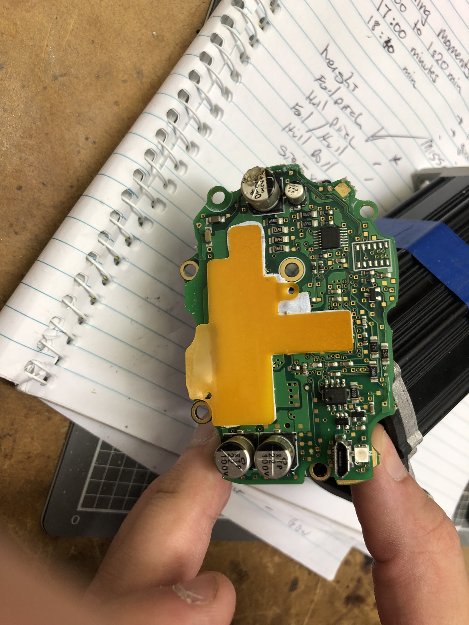 Rear of PCB with mosfets covered by white and orange thermal interface pad, electrolytic capacitors near edges, USB connector and LED