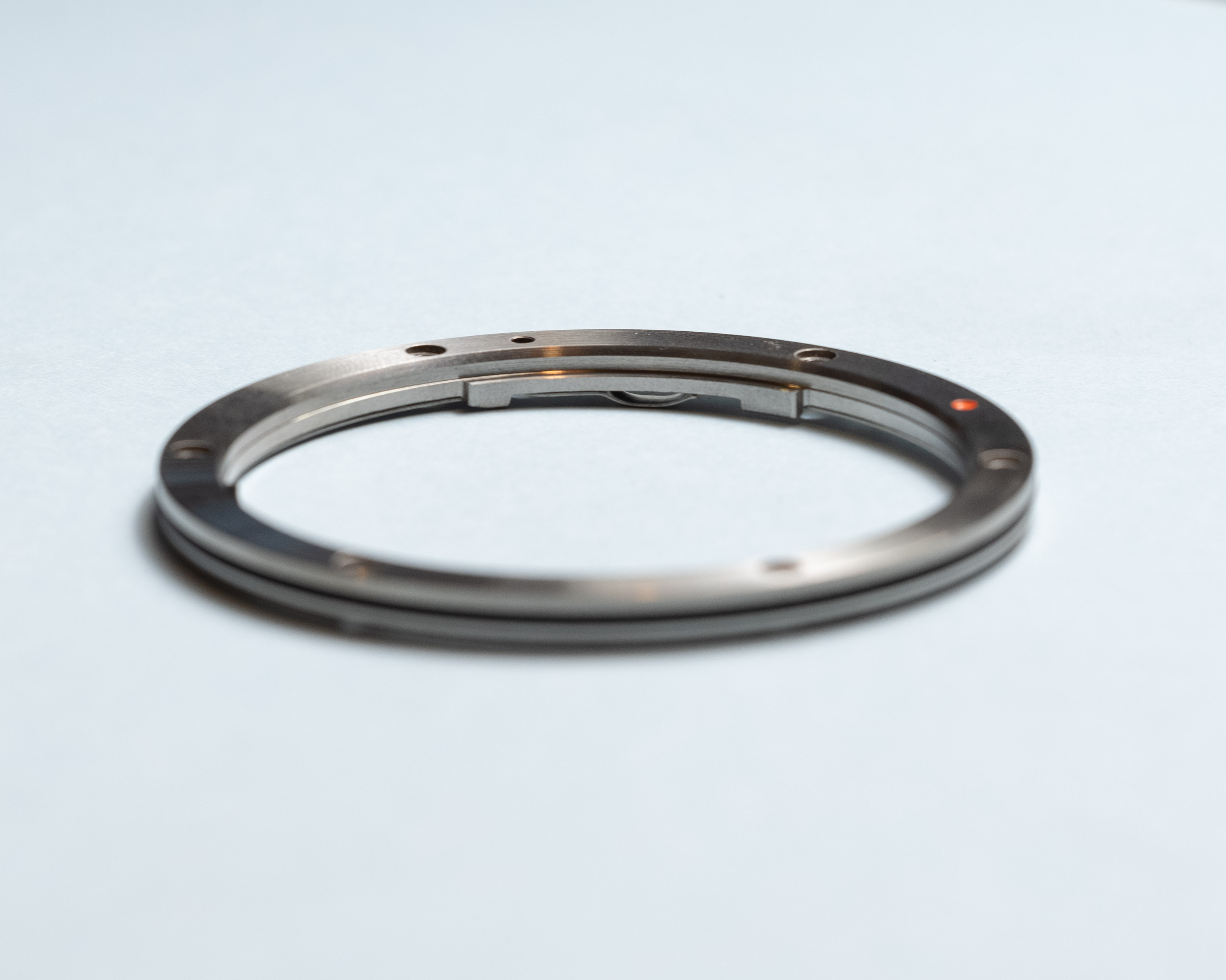 Side view of metal ring with polished silver appearance, flexible retention plate